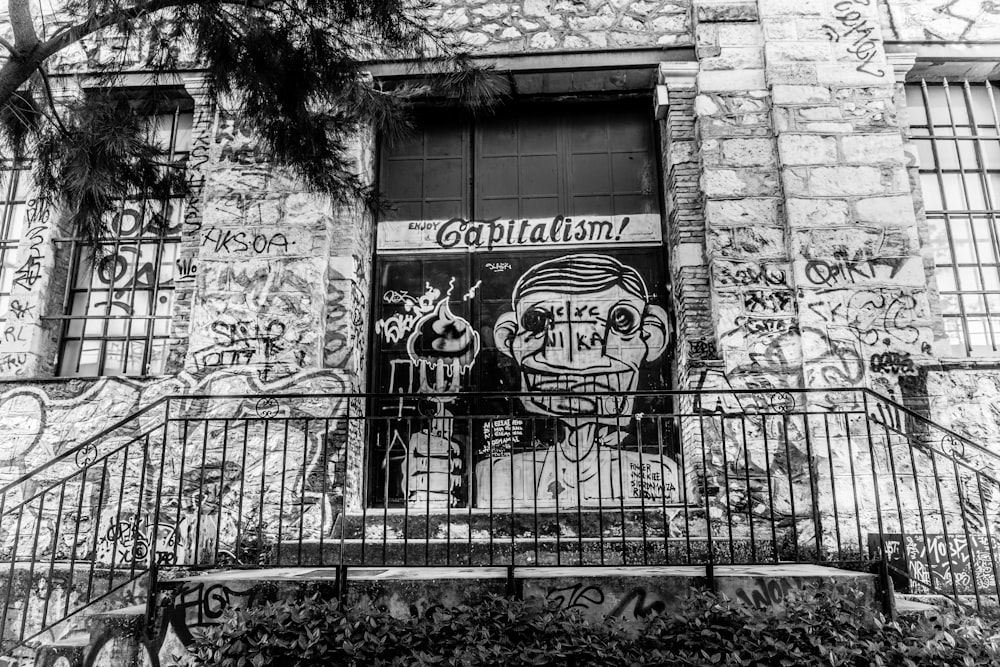 grayscale photo of concrete wall with graffiti
