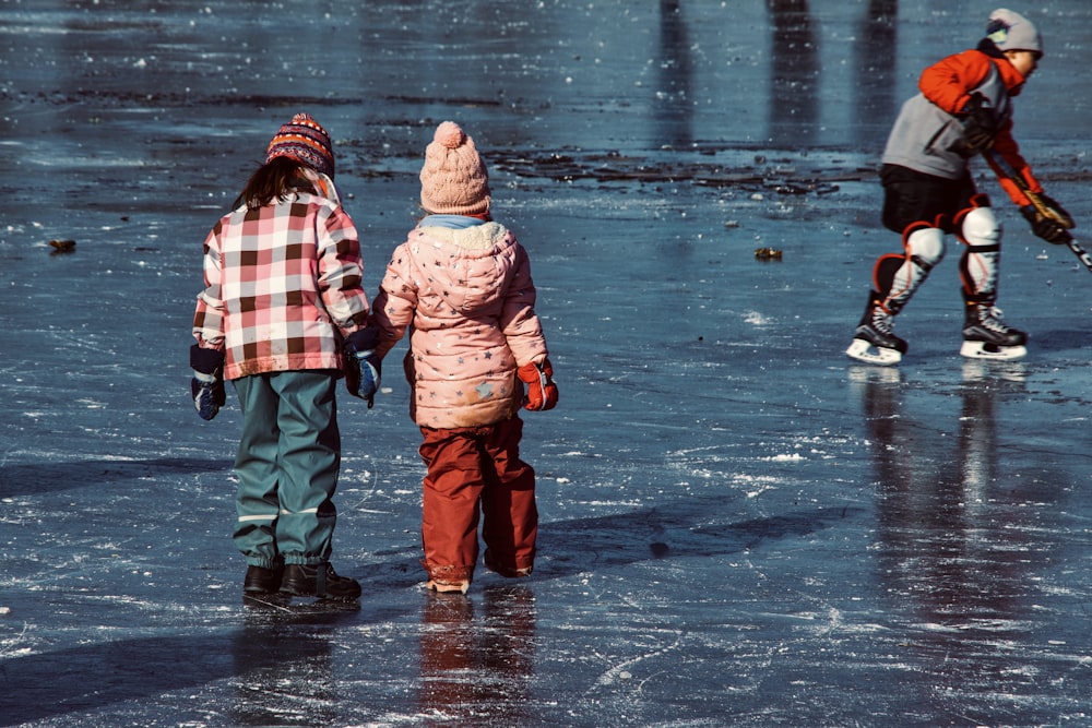 2 children in red and white jacket walking on wet road during daytime