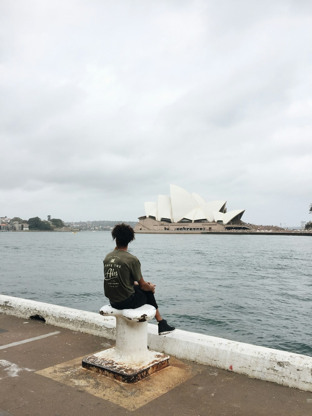 man in black jacket sitting on concrete bench near sea during daytime