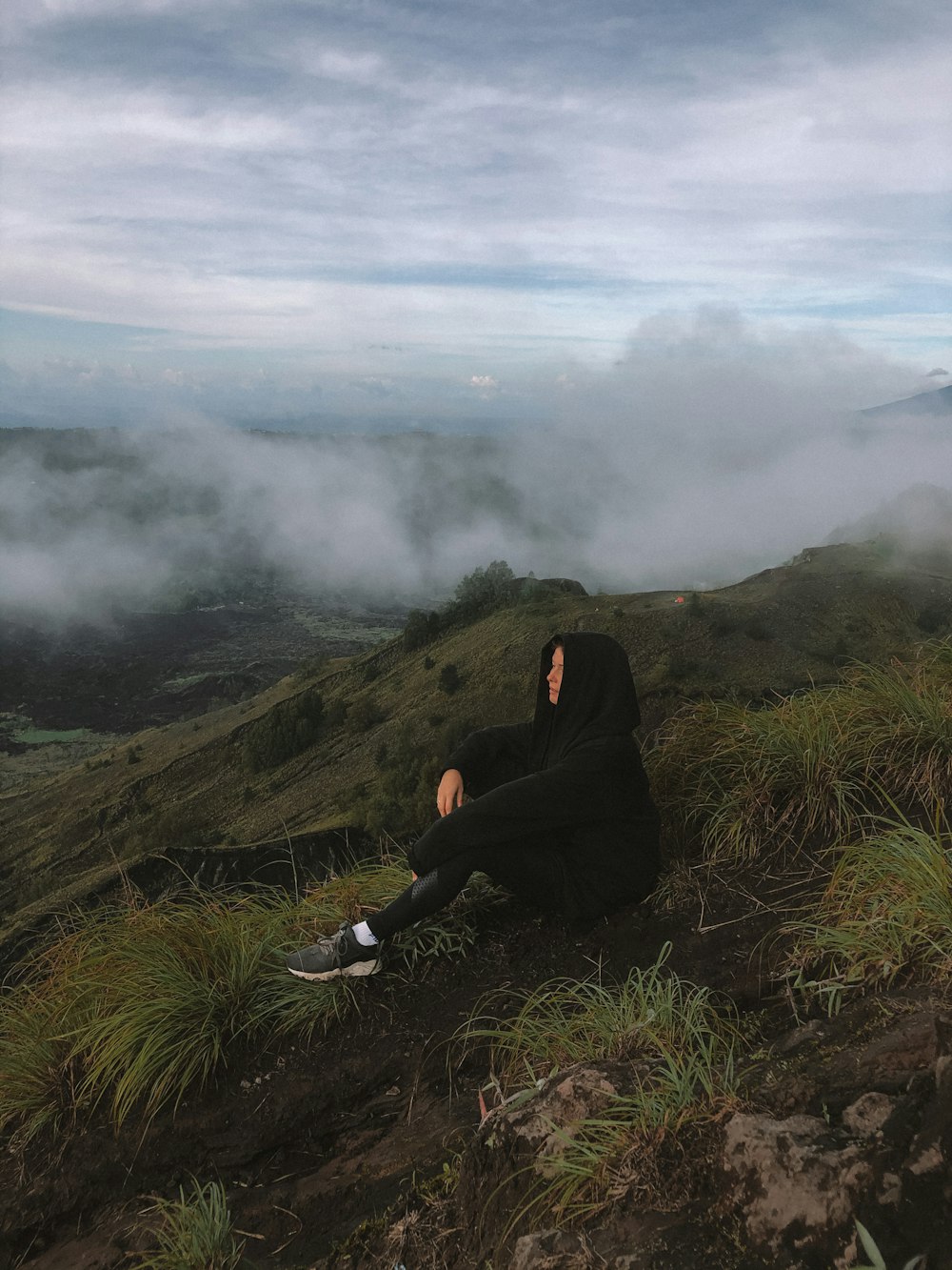 person in black jacket sitting on green grass field during daytime