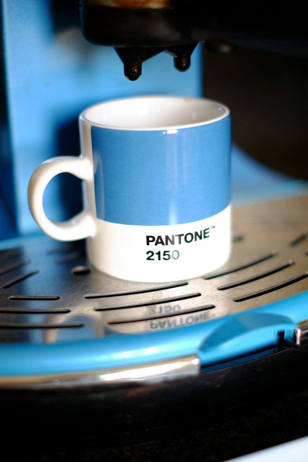 white and blue ceramic mug on silver steel table