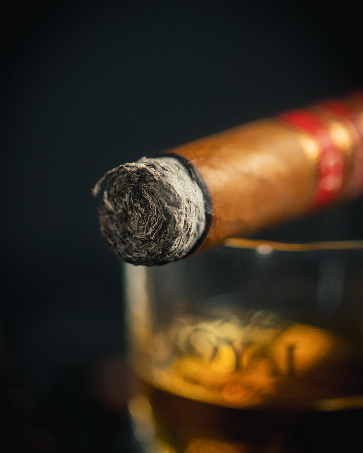 Hand-rolled cigar paired with whiskey under low warm lighting