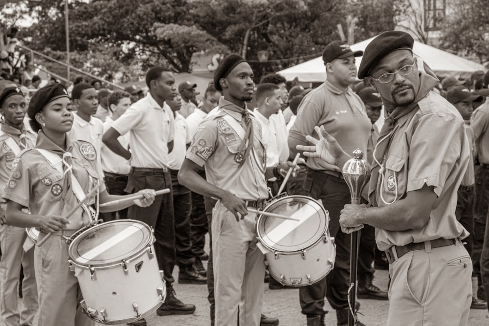 grayscale photo of men in white shirt and pants playing drum