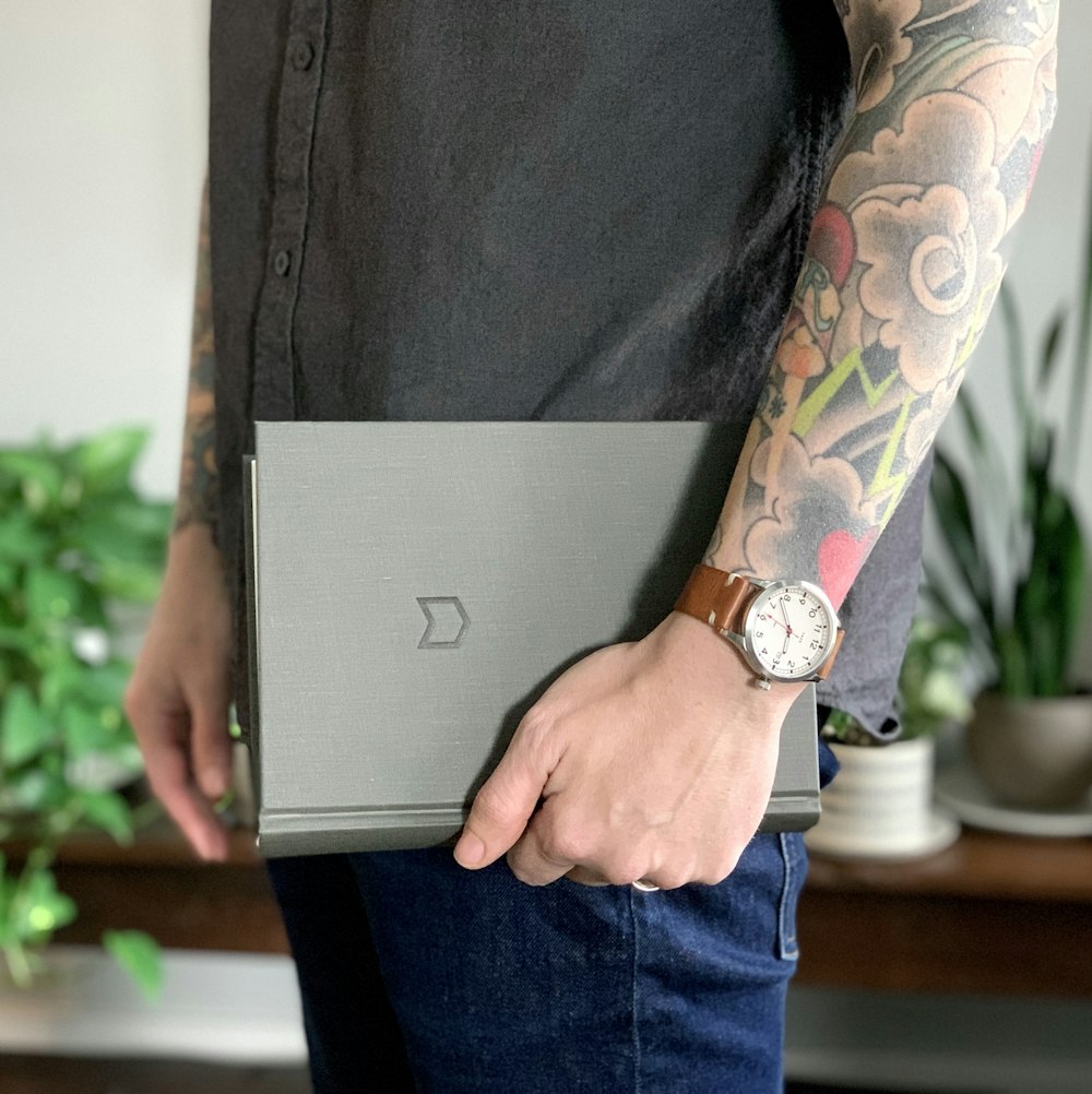 person in black shirt holding gray laptop computer