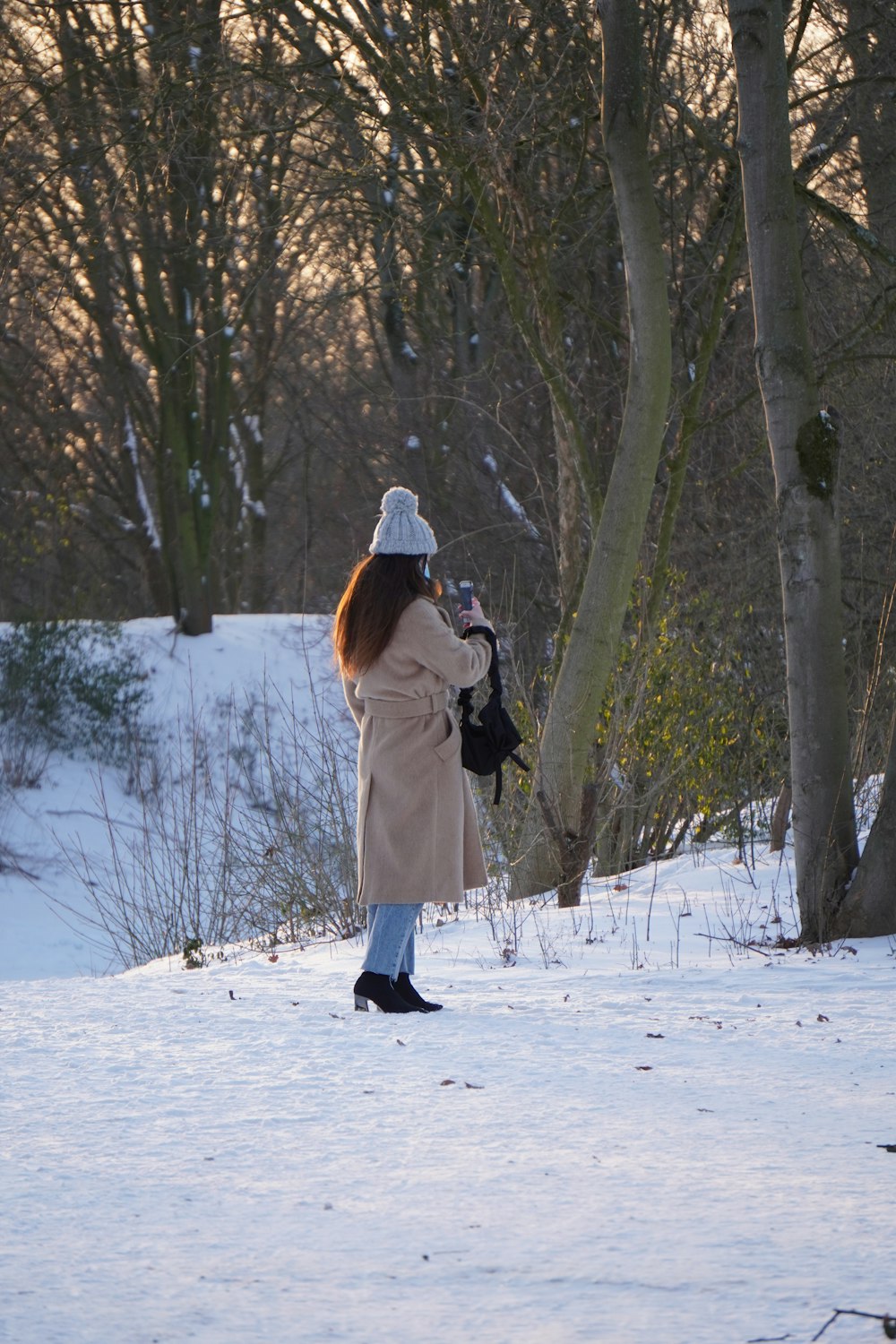 woman in white coat and black pants standing on snow covered ground