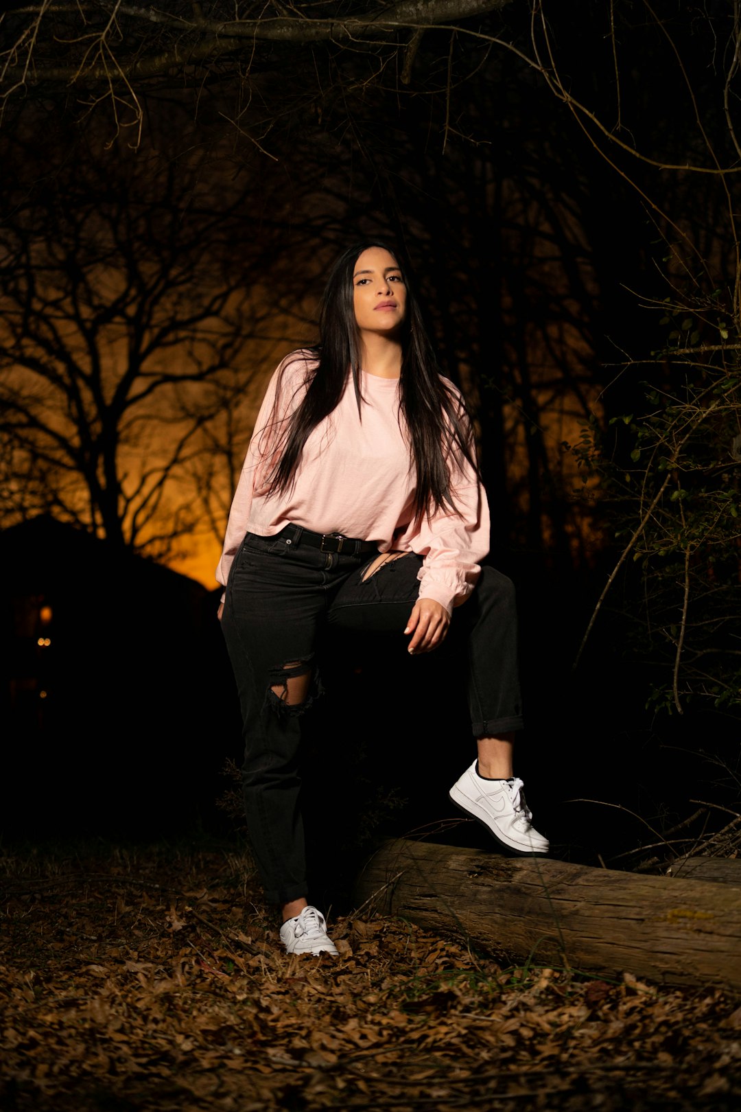 woman in white long sleeve shirt and black pants standing on forest during night time