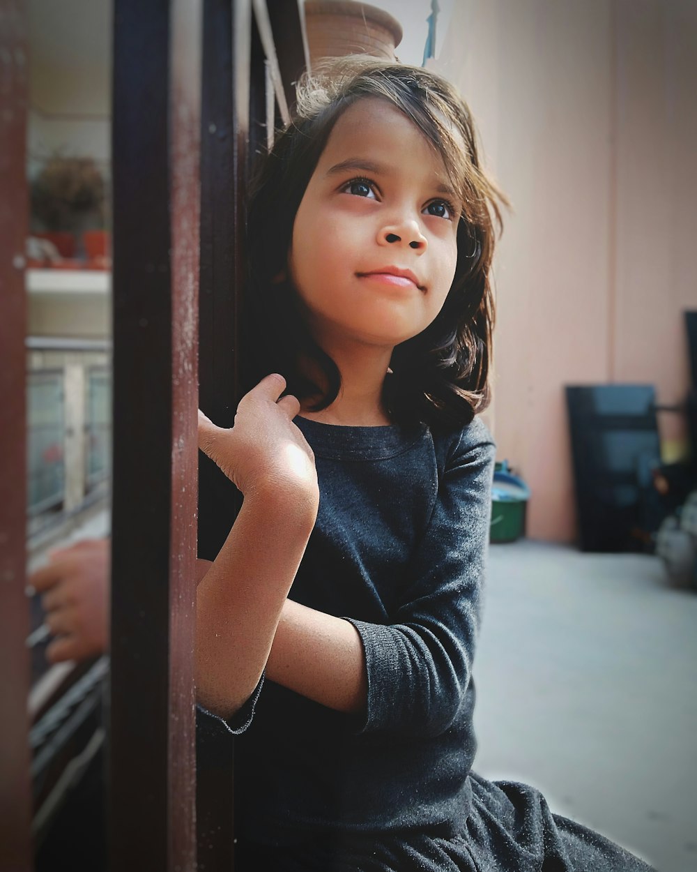 girl in blue crew neck t-shirt leaning on brown wooden framed glass window