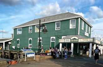 people standing in front of green and white building during daytime
