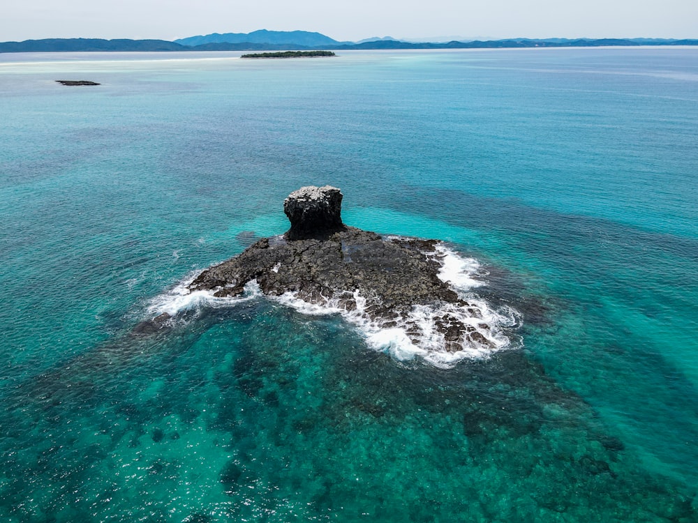 black rock formation on body of water during daytime