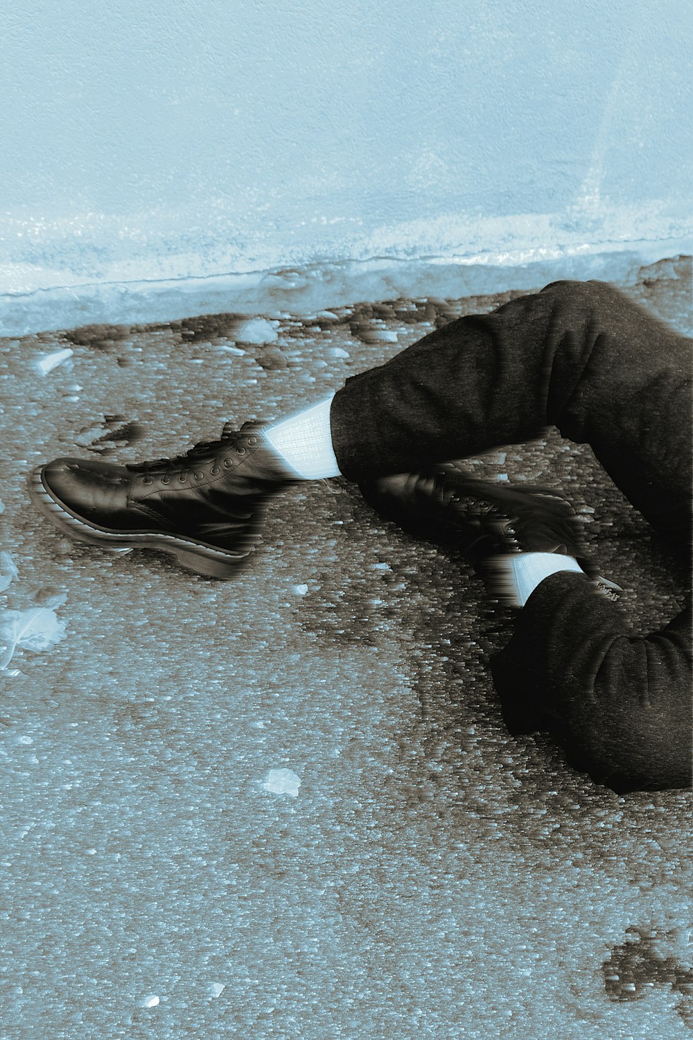 person in black pants and black leather shoes sitting on gray concrete floor