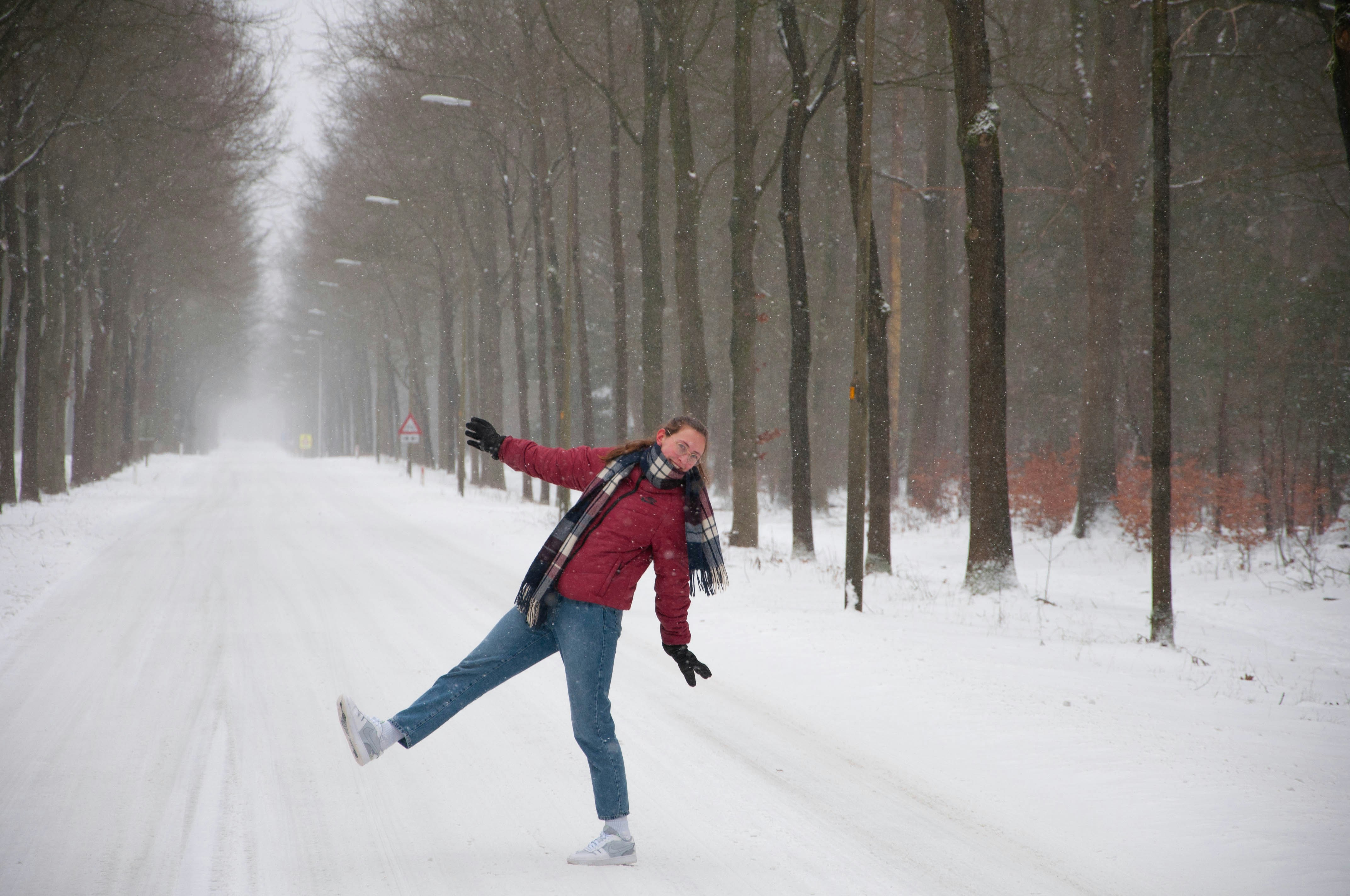 woman in black jacket and blue denim jeans walking on snow covered ground during daytime
