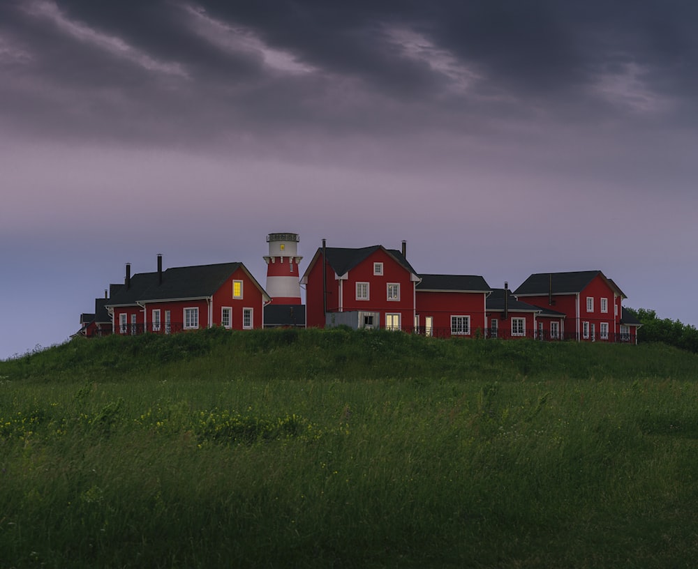 Casa roja y blanca en campo de hierba verde bajo nubes grises