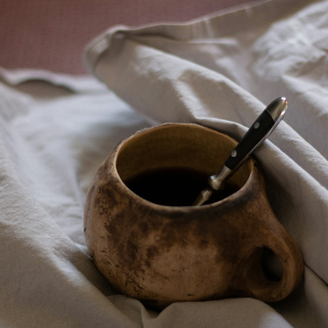 brown ceramic mug on white textile