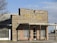 A rustic barbecue restaurant with a wooden facade displaying the sign 'Pody's BBQ'. The building has a covered entrance with metal bars on the windows and a combination of brick and wood materials. It's situated in a seemingly rural or small-town setting with clear skies.