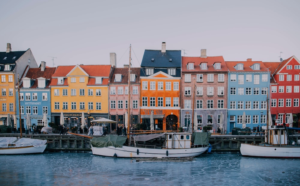 weißes und blaues Boot tagsüber auf dem Wasser in der Nähe von Betongebäuden