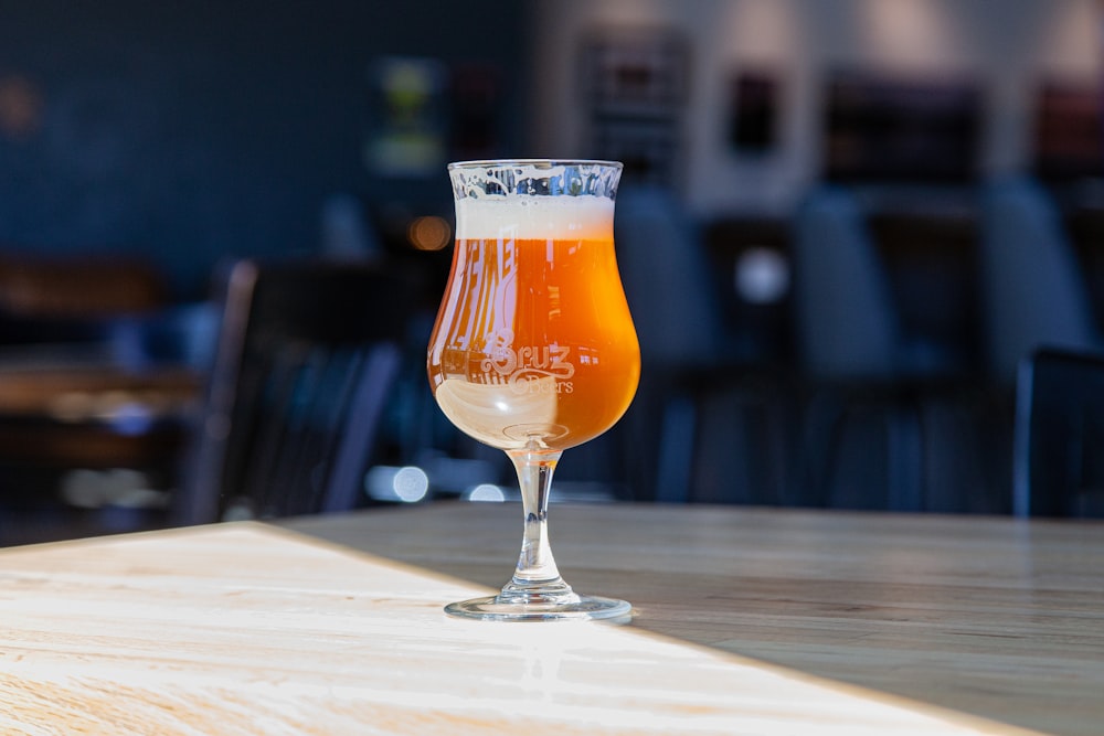 clear footed glass with brown liquid on table