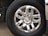 A close-up of a shiny, silver six-spoke truck wheel with the Chevrolet logo at the center, surrounded by black tire rubber engraved with the brand name Michelin. The reflective surface of the wheel captures parts of the surrounding environment.