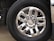 A close-up of a shiny, silver six-spoke truck wheel with the Chevrolet logo at the center, surrounded by black tire rubber engraved with the brand name Michelin. The reflective surface of the wheel captures parts of the surrounding environment.