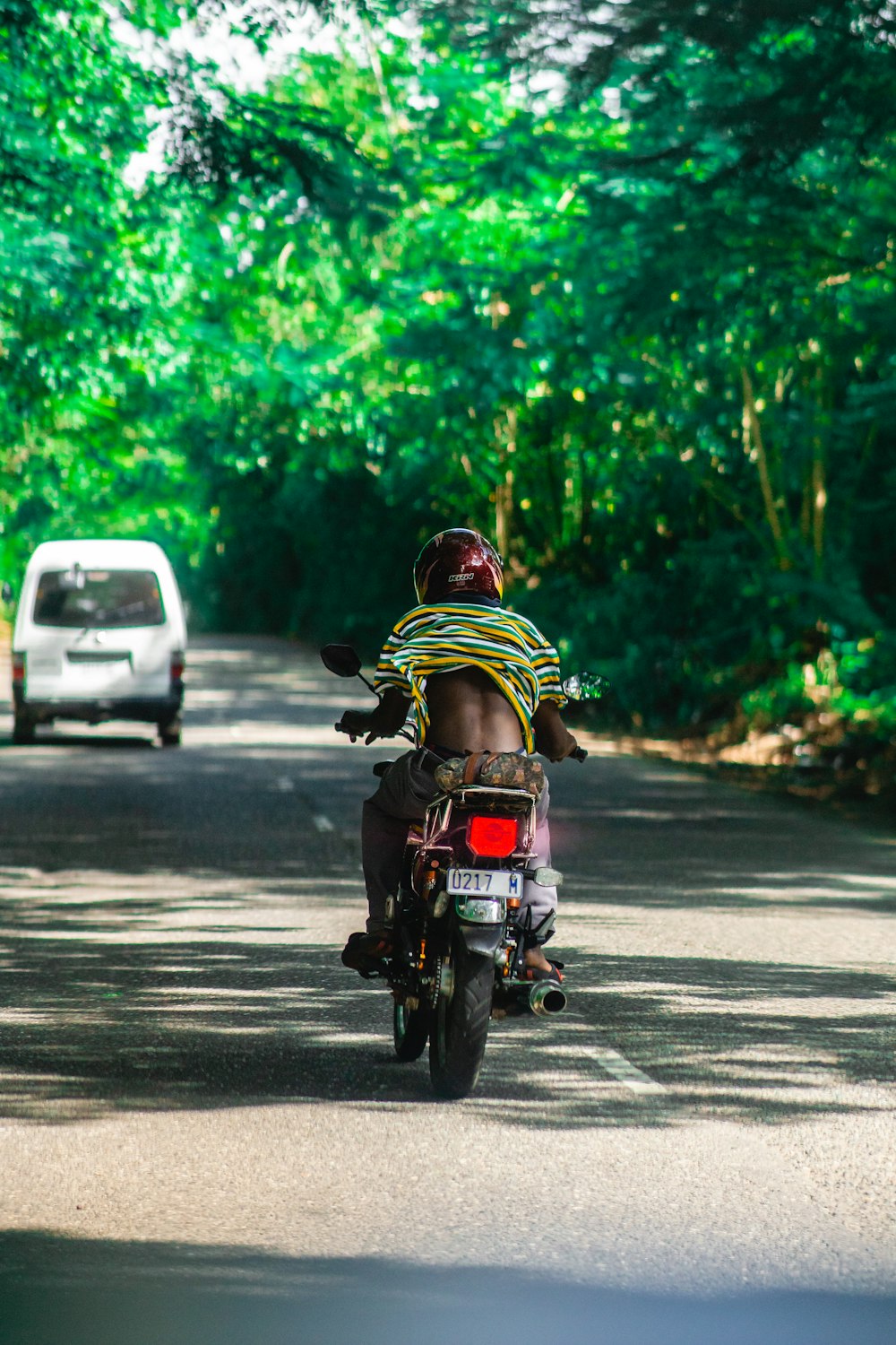 man in green and yellow shirt riding motorcycle on road during daytime