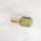 A glass bottle with a green liquid inside, labeled 'balance,' features a gold-colored cap. It is placed on a textured white fur surface.