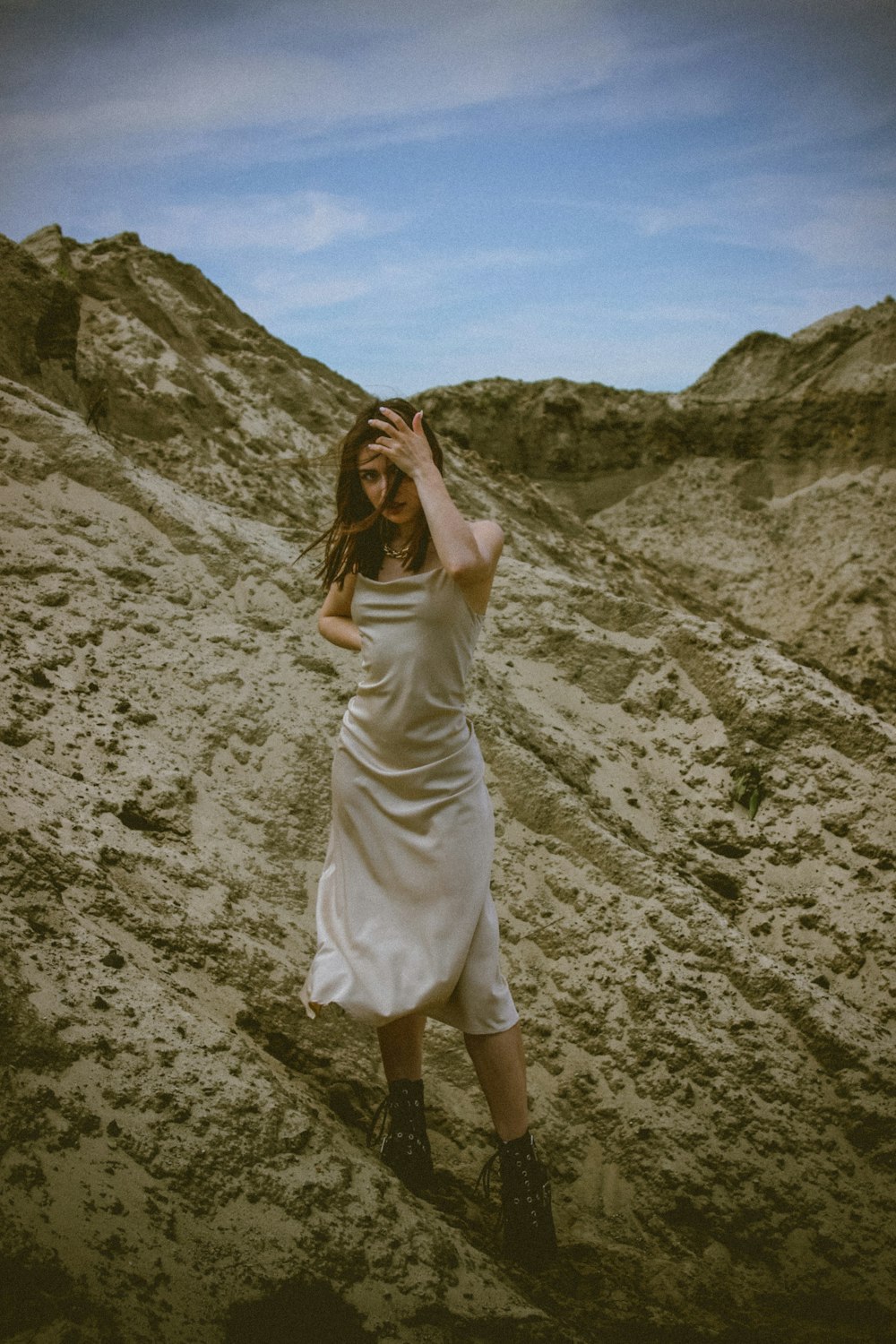 woman in white dress standing on rocky hill during daytime