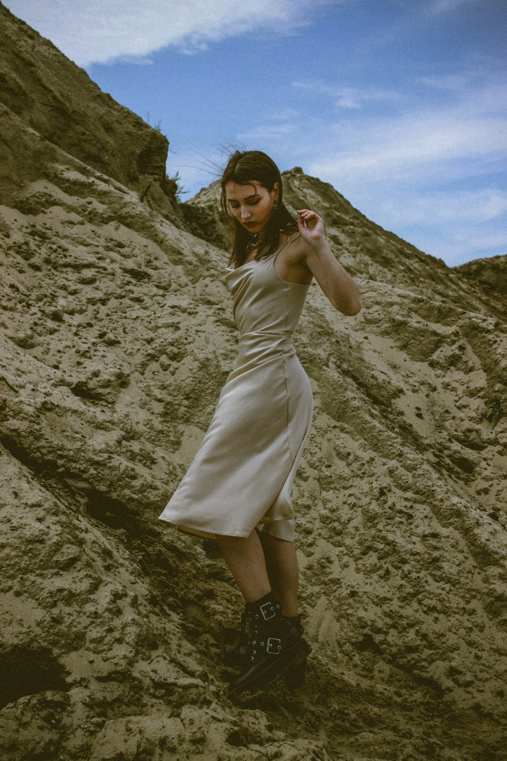 woman in white dress standing on rocky hill during daytime