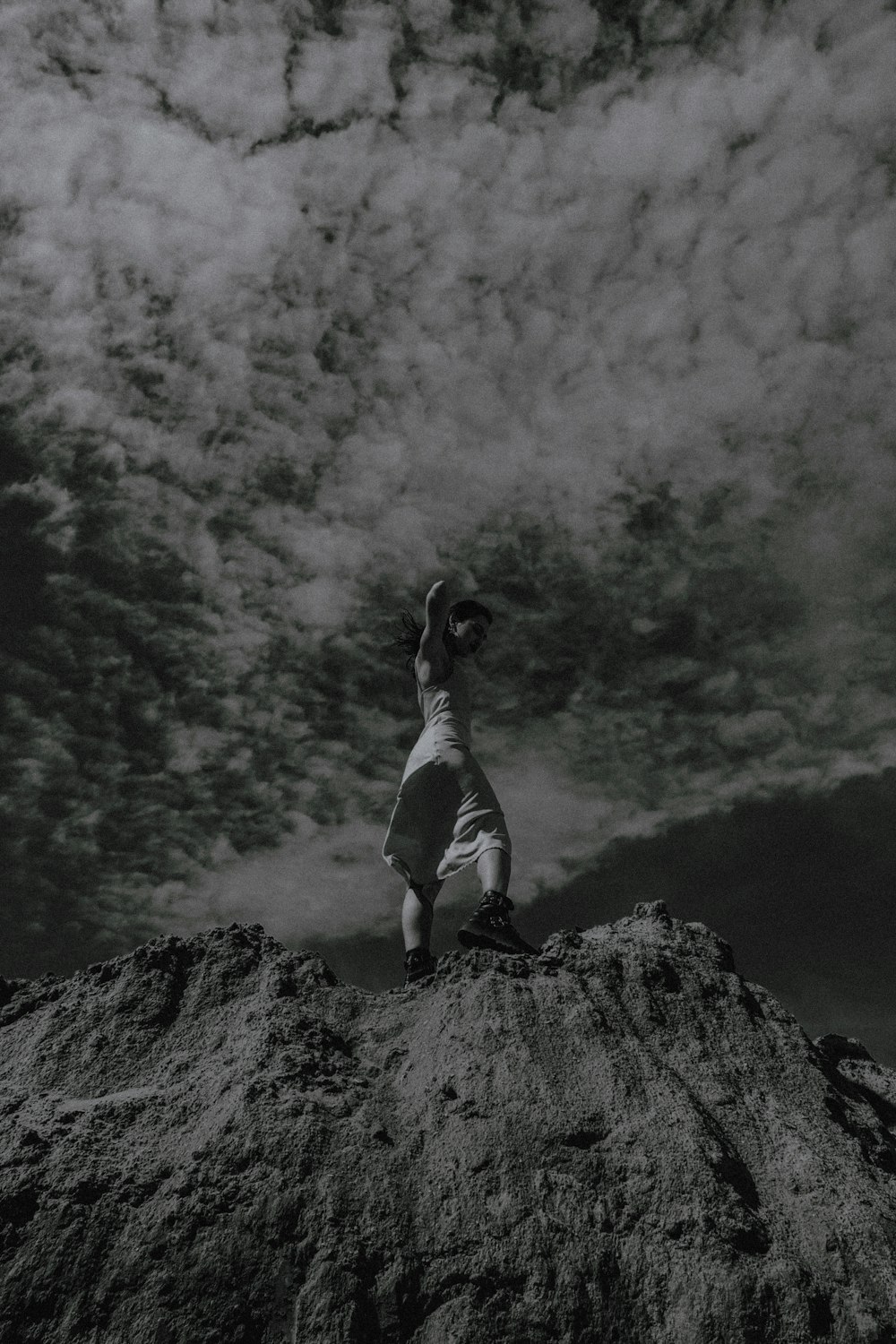 woman in white tank top and white pants standing on rock formation during daytime