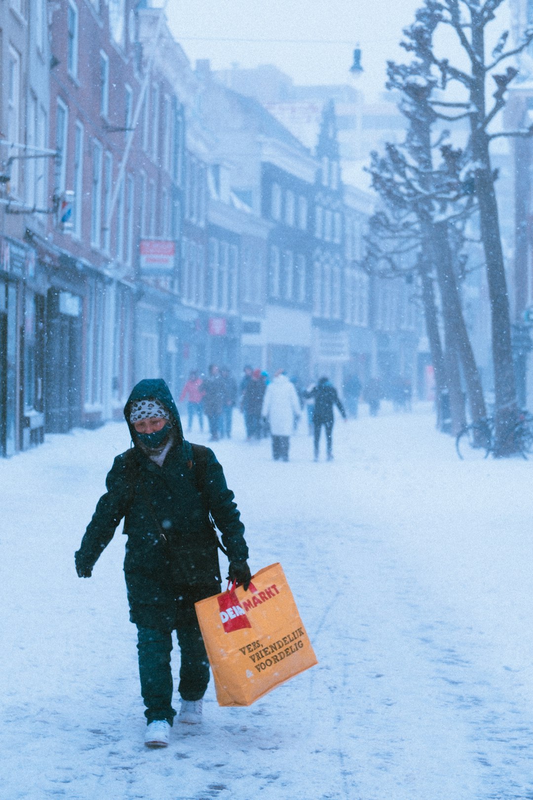 man in black jacket holding yellow plastic bag on snow covered ground