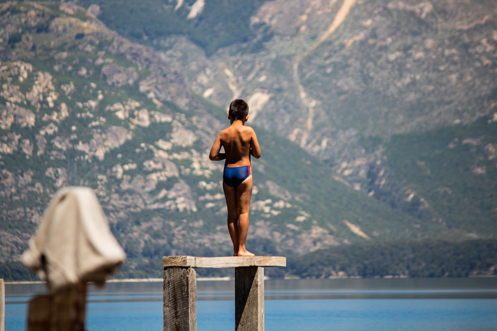 woman in blue sports bra and black shorts sitting on brown wooden railings during daytime