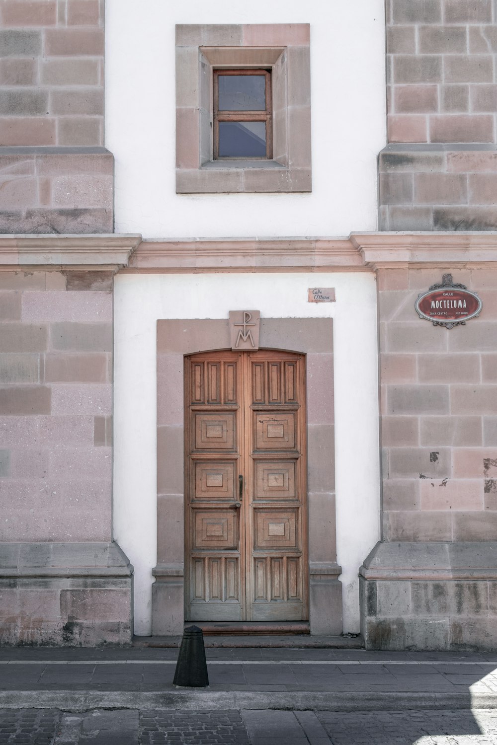 灰色のコンクリートの建物に茶色の木製のドア