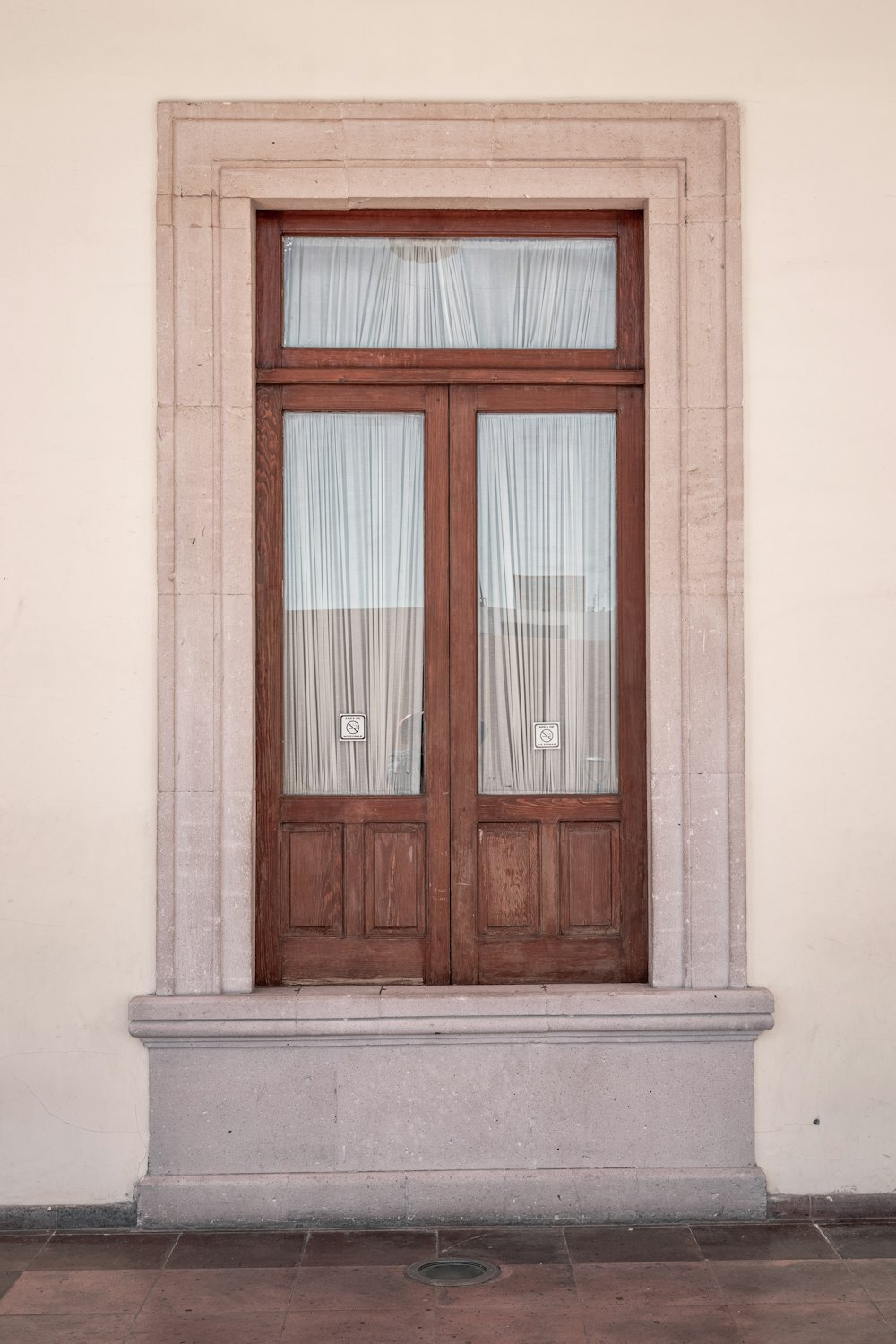 白いコンクリートの壁に茶色の木製の窓