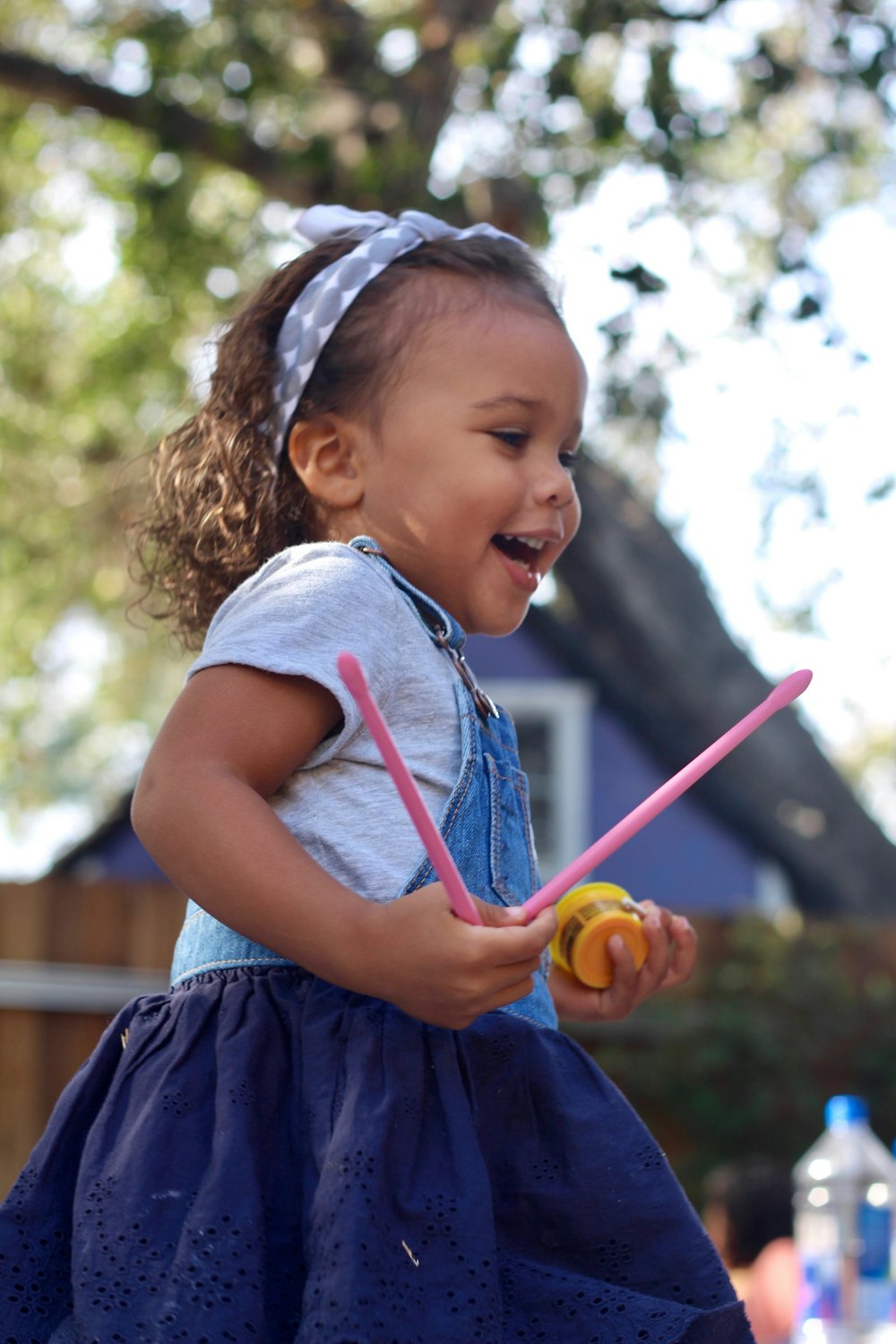 girl in blue and white dress holding orange and green plastic toy