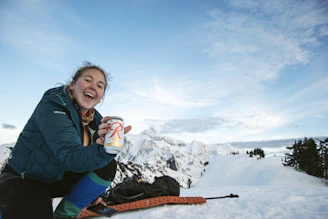 A happy customer outdoors, holding a Vayuo2 oxygen can with a scenic mountain backdrop.