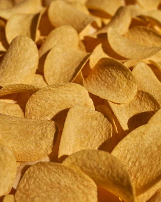 Close-up of crispy original flavor chips in yellow cream packaging on a natural wooden surface