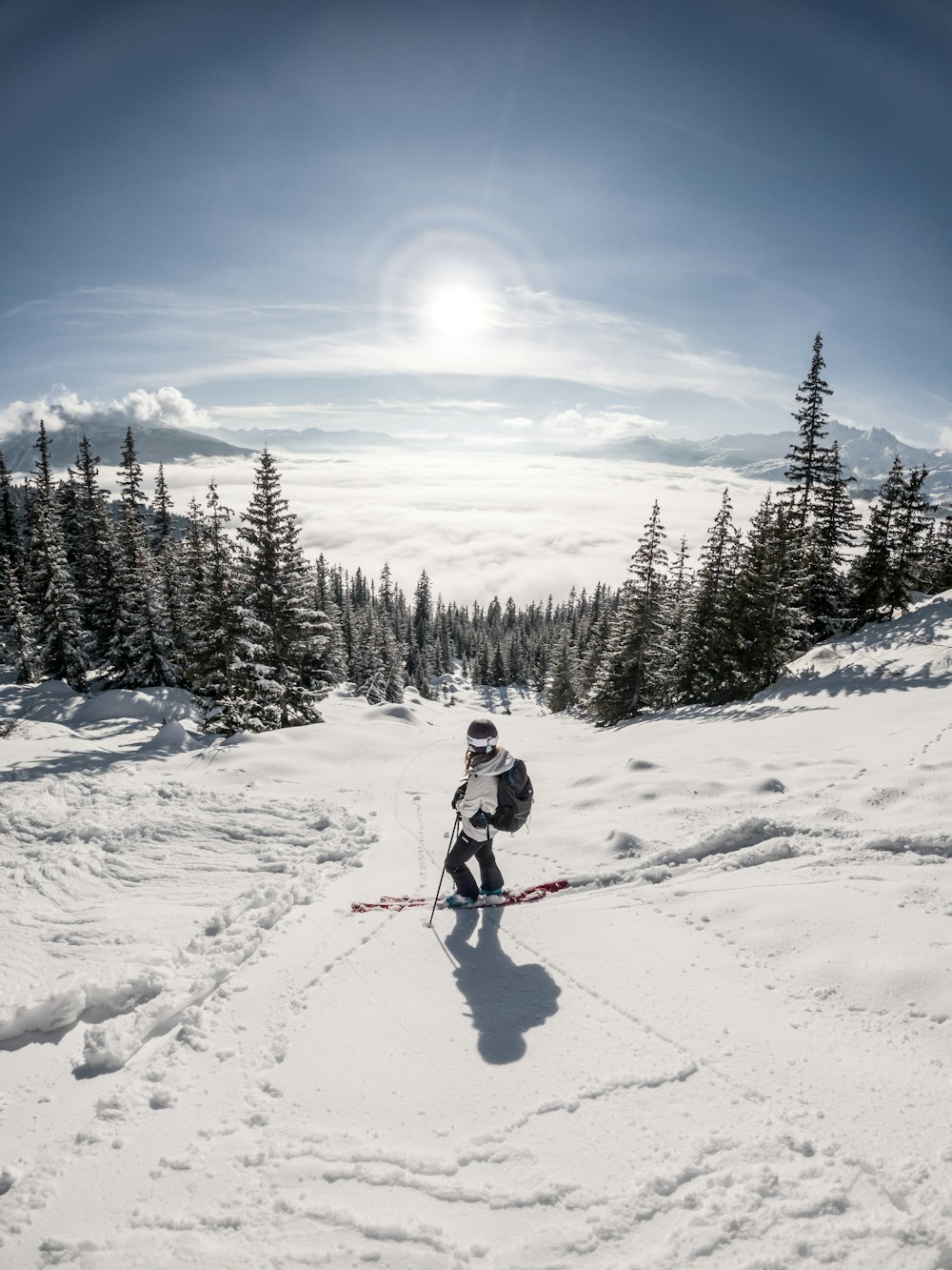 persoon in rode jas en blauwe broek die overdag ski-bladen berijdt op met sneeuw bedekte grond