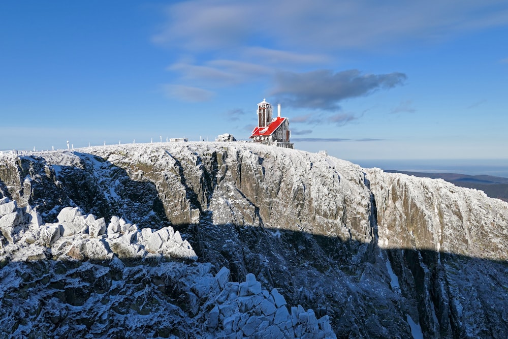 white and red lighthouse on gray rocky mountain under blue sky during daytime