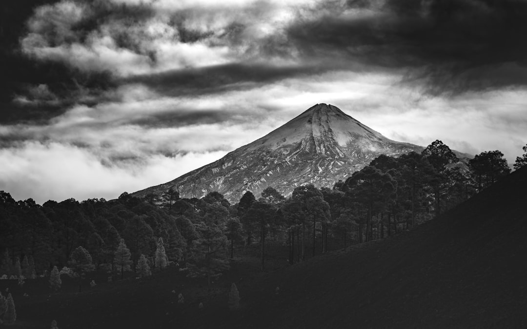 grayscale photo of mountain under cloudy sky