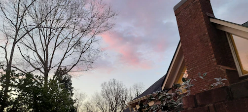 Evening shot of a completed roof replacement glowing warmly under porch lights in a quiet Billerica neighborhood.