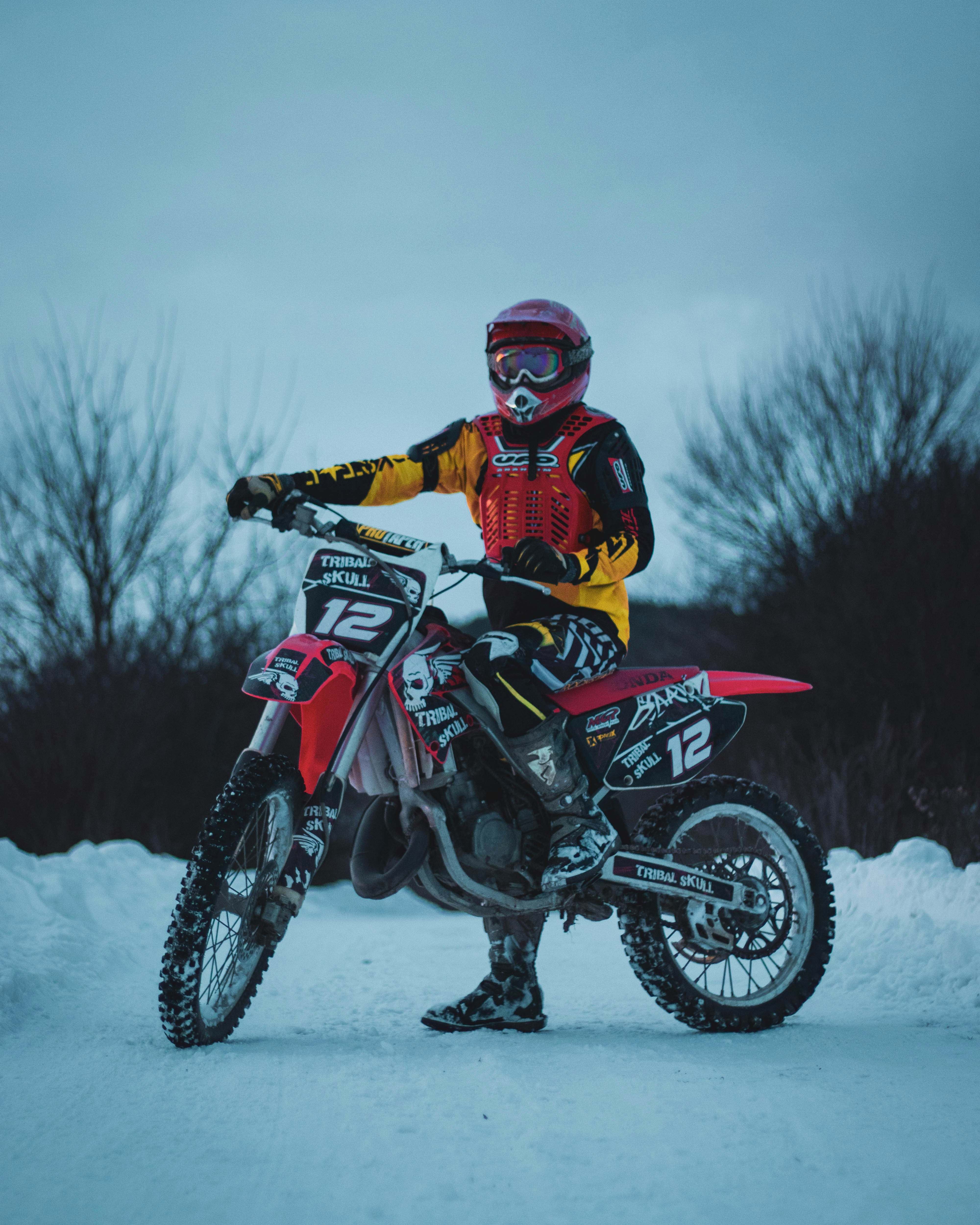 Man in red and black motocross suit riding motocross dirt bike on snow