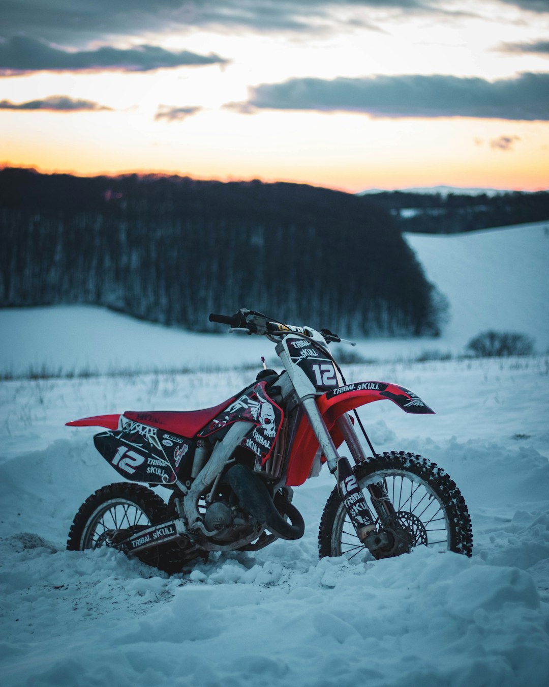 red and black motocross dirt bike on snow covered ground during daytime