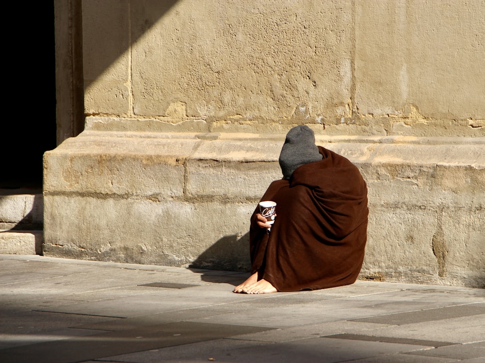 man in red robe sitting on gray concrete stairs