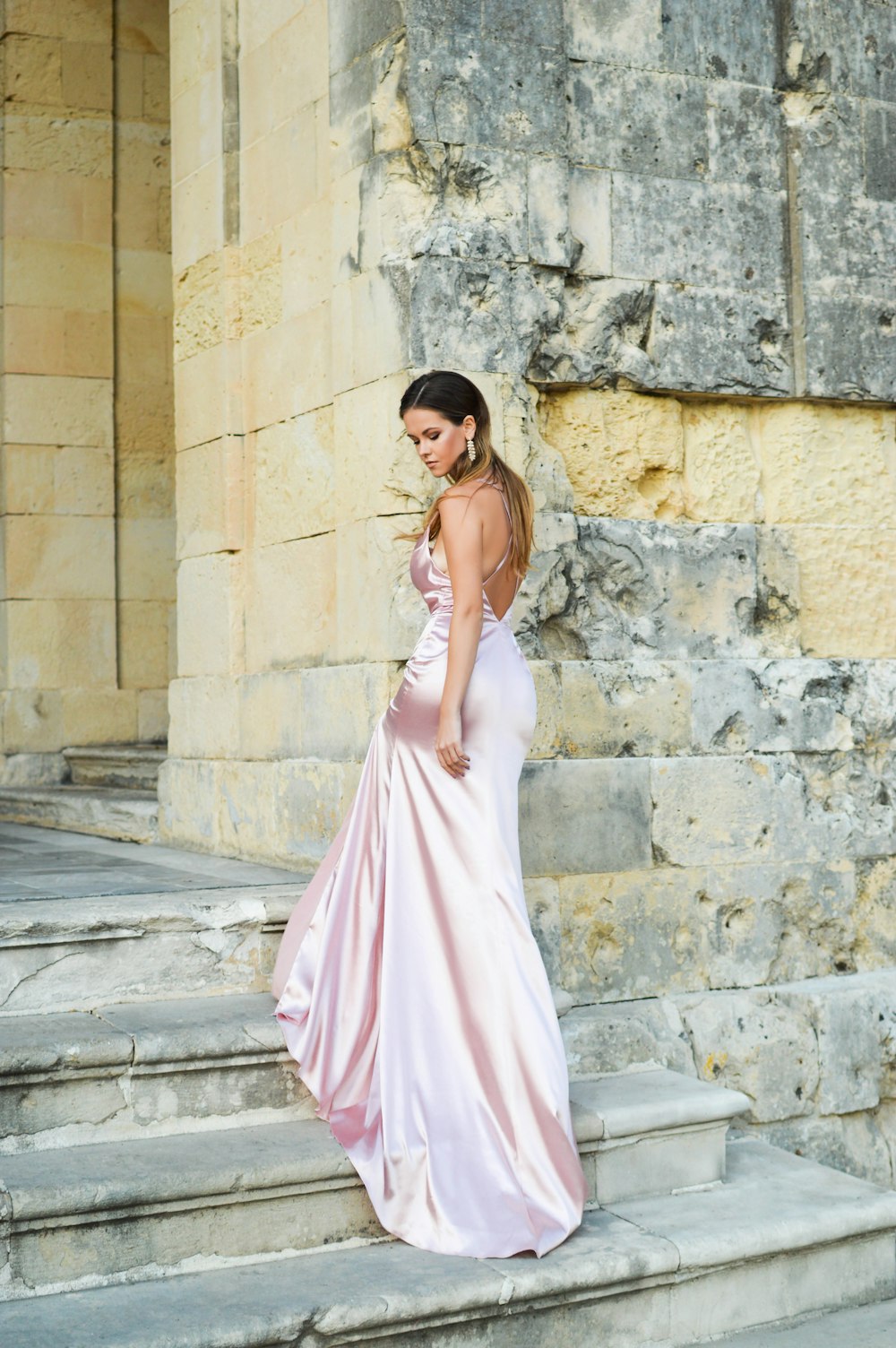 Femme en robe blanche sans manches debout sur un sol en béton gris pendant la journée