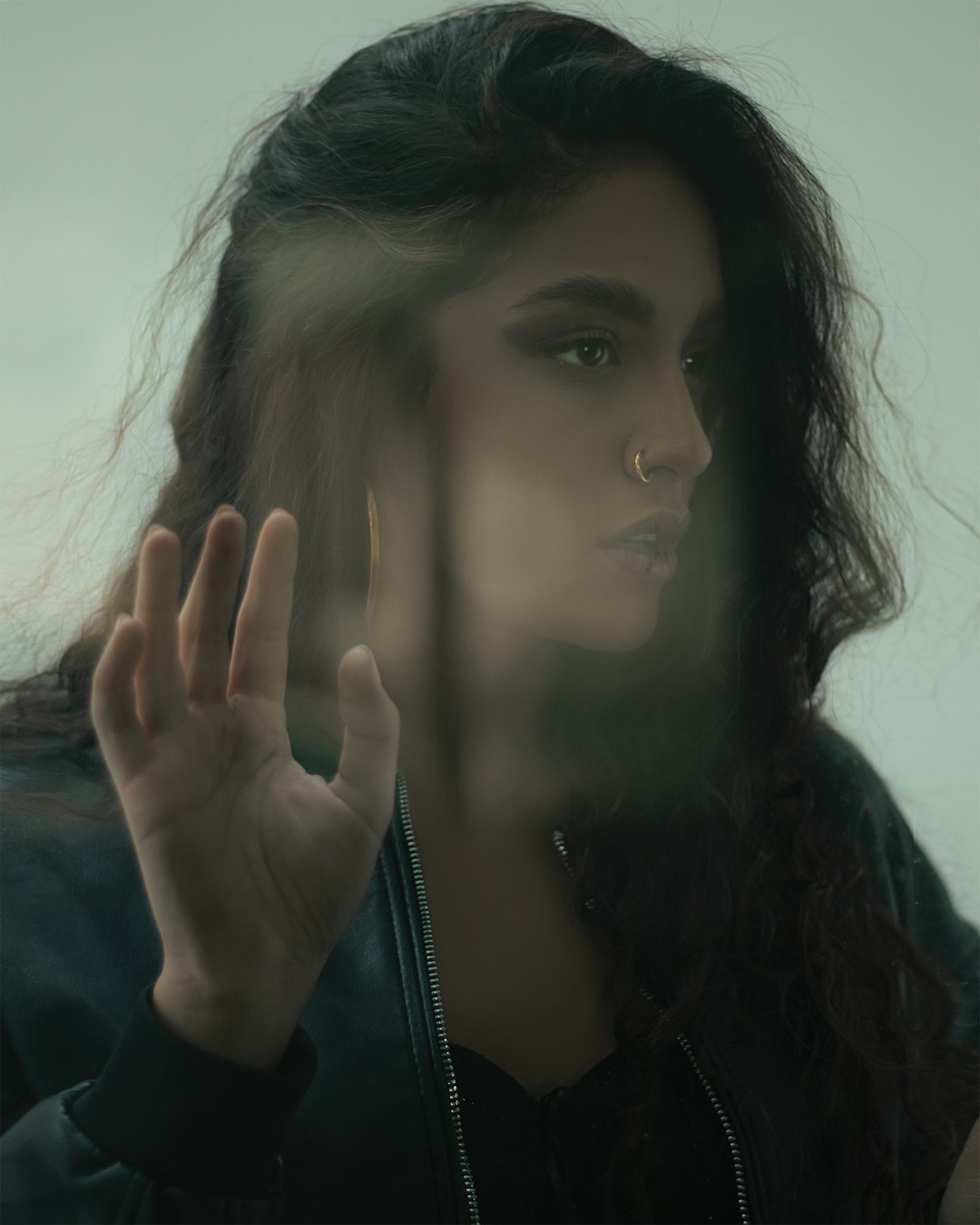 woman in black jacket covering her face