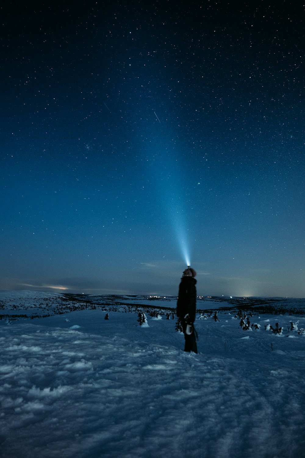 uomo in piedi su terreno coperto di neve sotto notte stellata