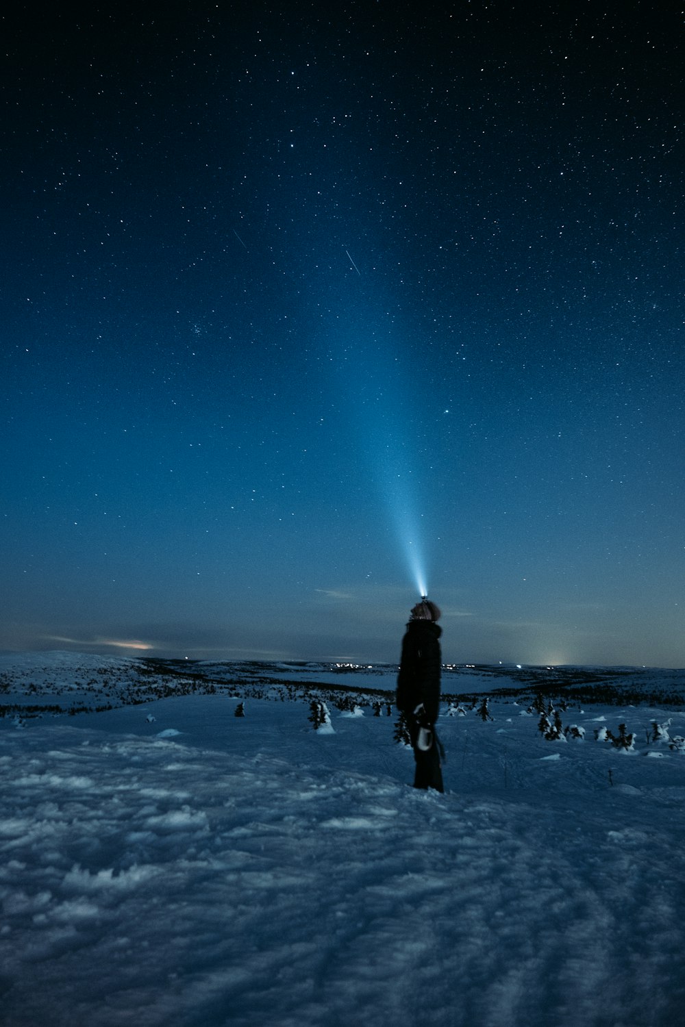 Mann steht auf schneebedecktem Boden unter sternenklarer Nacht