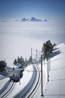 A luxury train winding through snow-capped mountains under a clear blue sky.