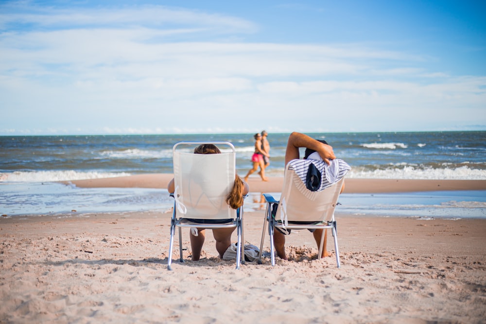 woman in black and white stripe dress sitting on white chair on beach during daytime