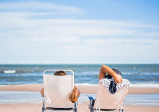 woman in black and white stripe dress sitting on white chair on beach during daytime