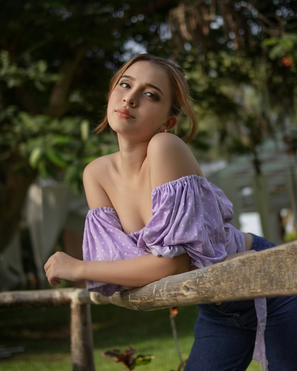 woman in purple spaghetti strap dress sitting on brown wooden bench during daytime