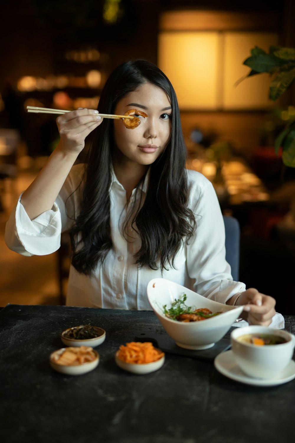 白い長袖シャツを着て食べる女性